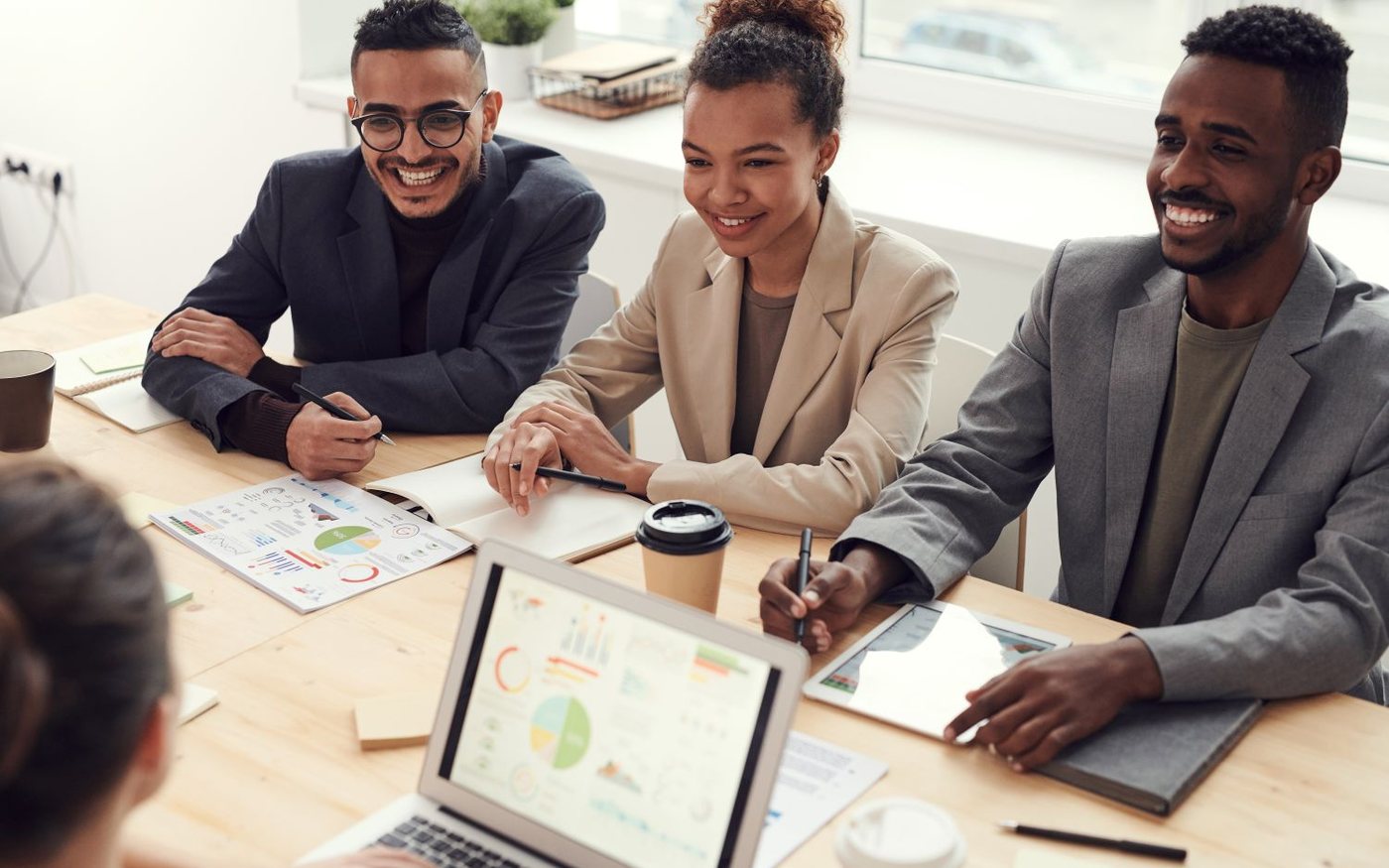 Product managers smiling during a user research and roadmap discussion with charts and laptops.